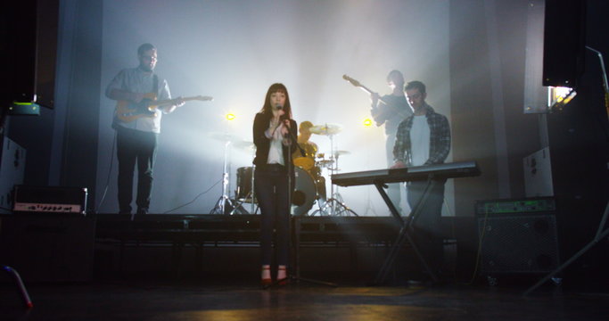 Attractive young female singer performing with band at live music event