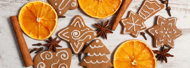 Fresh baked decorated gingerbread with spices on old wooden background, christmas time