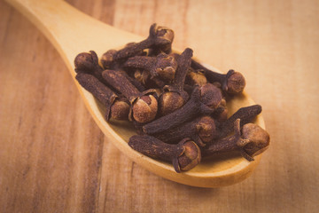 Vintage photo, Heap of cloves with wooden spoon on table, seasoning for cooking