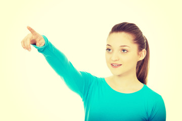 Smiling young woman pointing up.