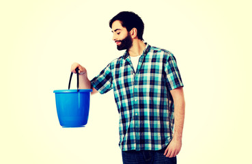 Handsome man looking into plastic bucket.