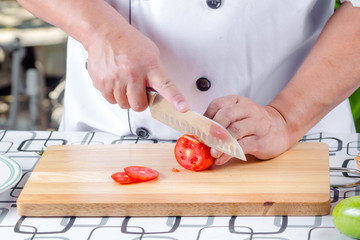 Chef cutting tomato