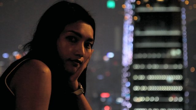 Portrait of a woman at the background illuminated skyscrapers at night