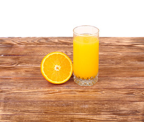 Glass of freshly pressed orange juice with sliced orange half on wooden table