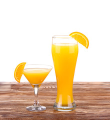 Glass of freshly pressed orange juice with sliced orange half on wooden table
