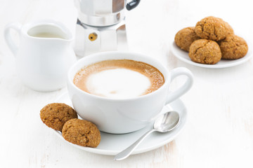 cup of cappuccino and macaroons on white table