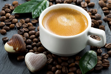 cup of espresso on coffee beans background and chocolate candies