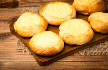 Yeast buns with cheese, traditional russian pastry, on the wooden background.