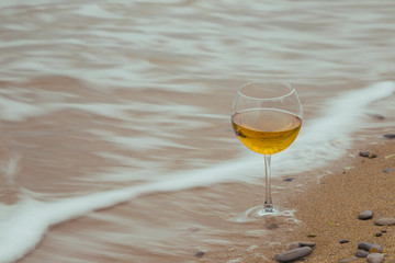 Romantic glass of wine sitting on the beach, overcast autumn wea