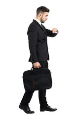 Side view of walking businessman checking hand watch time. Full body length portrait isolated over white studio background.