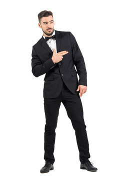 Funny secret agent with finger gun hand gesture looking away. Full body length portrait isolated over white studio background.