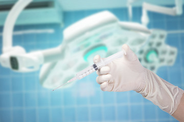 holding syringe on surgical room background