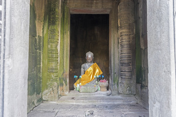 Obraz premium Buddha's statue between column of Angkor Wat