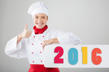 Beautiful smiling woman chef showing sign finger and holding a sign 2016