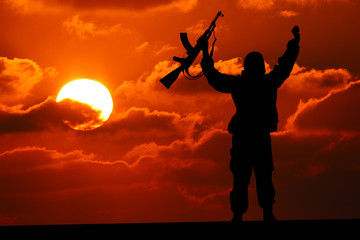 Fototapeta na wymiar Silhouette of military soldier or officer with weapons at sunset. shot, holding gun, colorful sky, mountain, background