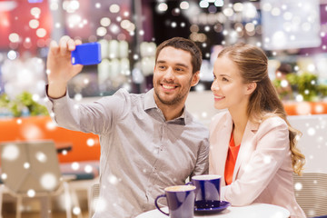 happy couple with smartphone taking selfie in mall