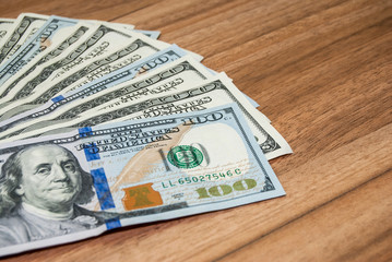 one hundred dollar bills on wooden table