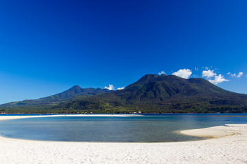 Fototapeta na wymiar Island with white sand and volcano in the background