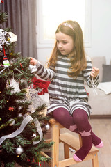 Obraz na płótnie Canvas Young girl decorating the Christmas tree