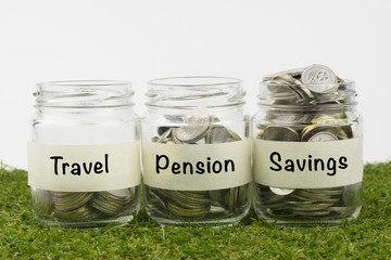 Coins in glass jar contains coins for travel, pension and savings. financial concept