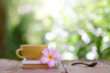 yellow coffee cup with flower and wooden spoon on wooden table