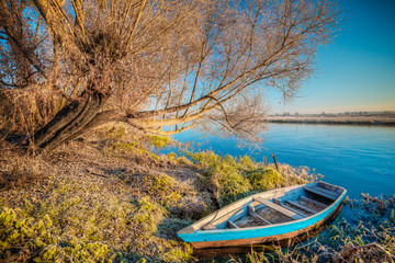 Obraz premium River and old wooden rowing fishing boat at beautiful sunrise in