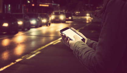 Using cellphone outdoors - with defocused city traffic.