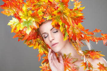 Naklejka na ściany i meble Beautiful woman wrapped in autumn leafs