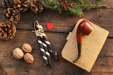 Christmas concept - chocolate roll, walnut, pine cone, note book, smoking pipe and fir tree - winter concept