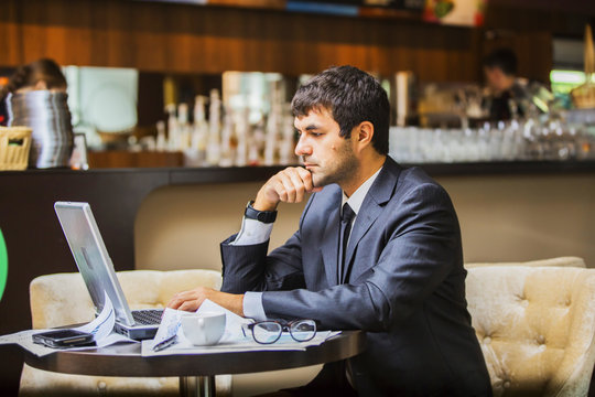 мужчина в деловом костюме с вдохновением работает на ноутбуке, рядом чашка кофе