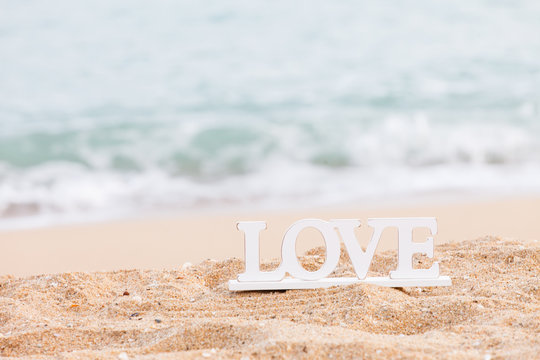 wooden letters spelling the word love on a tropical beach