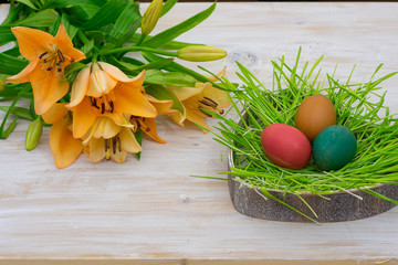 Still life for Easter with lilies, spring grass, eggs in wooden table