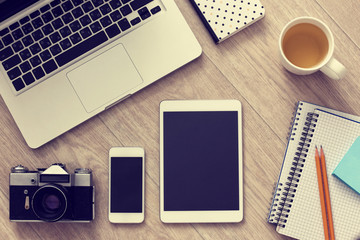 Laptop, smartphone, tablet, vintage camera and cup of tea on woo
