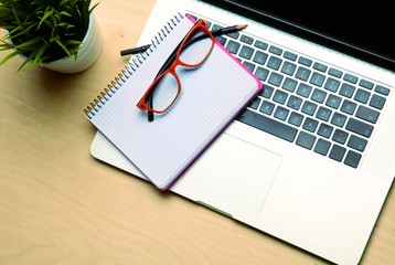 Office table with blank notepad and laptop 