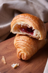Closeup of croissant with jam on a wooden background. selective focus.