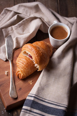 Croissant with jam and coffee on a wooden background. Top view.