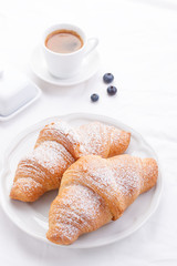 .Couple of croissants on a white plate with coffee and berries. selective focus.