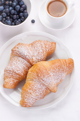 Couple of croissants on a white plate with coffee and berries with copy space. top view