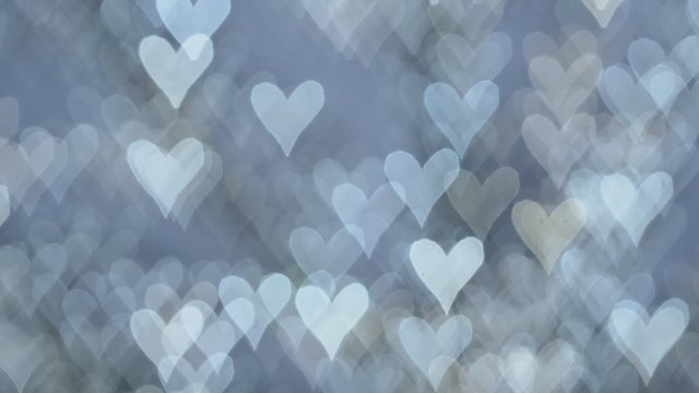 cold white lights on defocused blue background in a form of glimmering hearts 