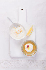 Lemon jelly with cream and jam in a glass on a white board. Top view.