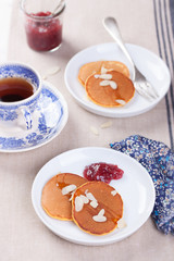 Pumpkin pancakes with honey, nuts and jam in a white plate on a table.