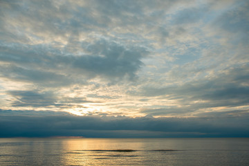 Naklejka na ściany i meble Summer sunset on the beach with clouds over the sky