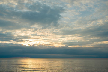 Fototapeta na wymiar Summer sunset on the beach with clouds over the sky