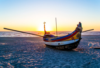 Fishing boat on a sandy beach. Sunset on the ocean. Portugal.