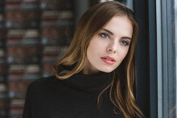 Naklejka premium Sensual thoughtful young female dreaming near the window