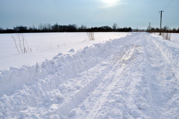 Fototapeta na wymiar Snow covered rural road and tire tracks