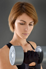 Portraitn of woman in crossfit gym lifting dumbbell, isolated