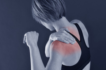 Closeup of fitness girl with shoulder pain, isolated