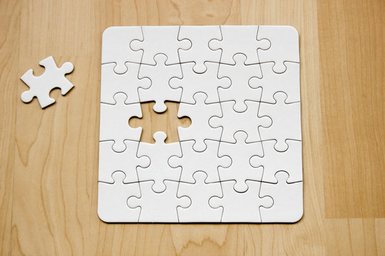 Letztes Teil eines wei&szlig;en Puzzles auf Holuntergrund