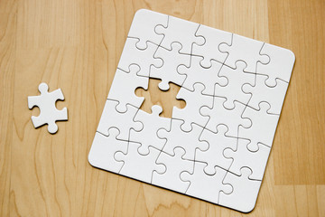 Letztes Teil eines weißen Puzzles auf Holuntergrund